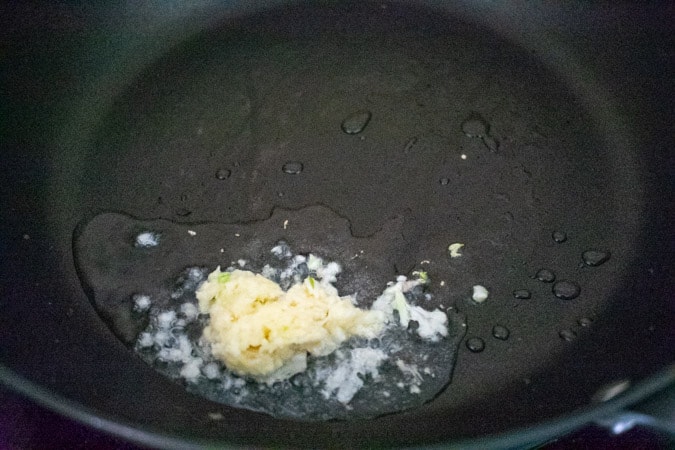 fresh garlic frying in oil in black pan