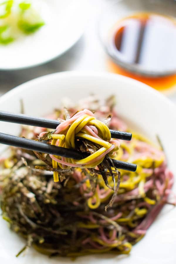 purple and green soba noodles on chopsticks