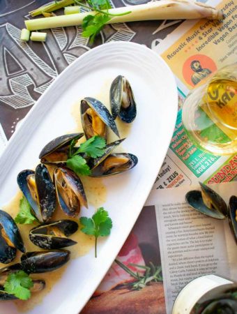 Easy Thai Coconut Curry Mussels on white plate with white wine glass