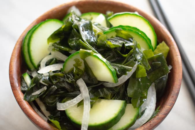 Korean seaweed salad in wood bowl with black chopsticks on the side.