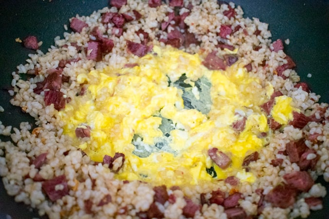 Scrambled eggs in the center of the wok with corned beef fried rice around it. 