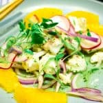 Aguachile ceviche with orange slices on a blue plae