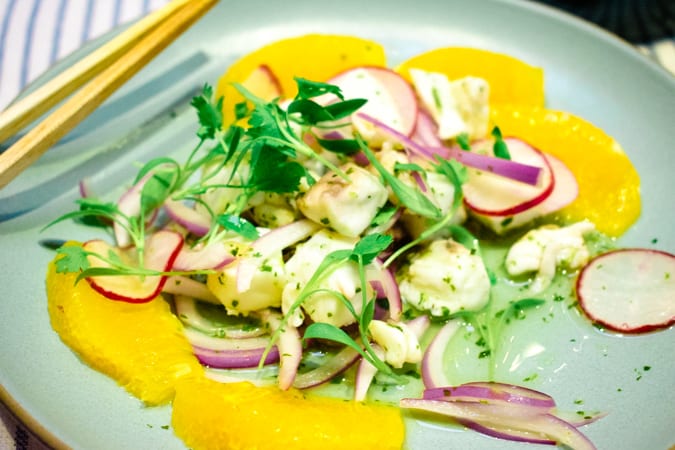 Aguachile ceviche with orange slices on a blue plae