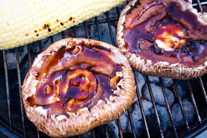 2 portabella mushrooms with BBQ sauce on a charcoal grill