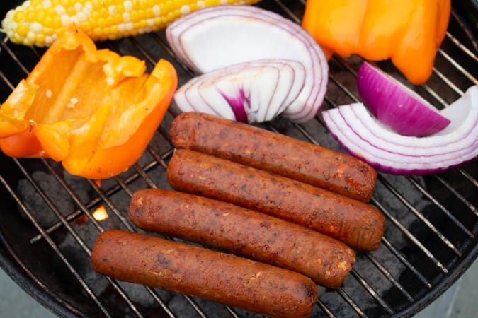Vegan Field Roast Mexican Chorizo Sausages on the grill with red onion and yellow bell pepper