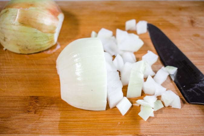 half chopped onion and knife on a cutting board