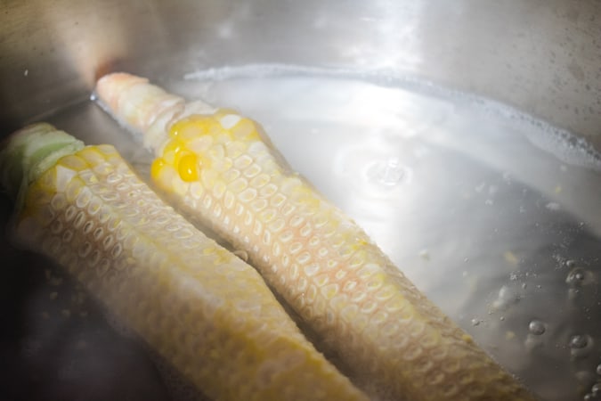 Corn cobs simmering in water in a pot for corn stock