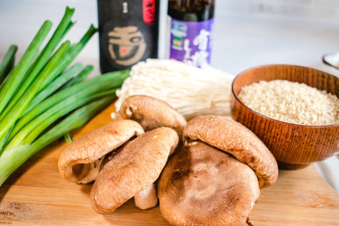cutting board with mushrooms, rice, green onion, and soy sauce