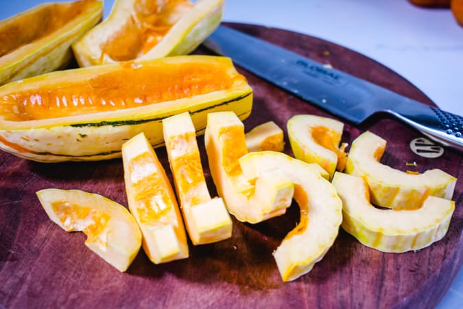 Sliced delicata squash on a cutting board with knife