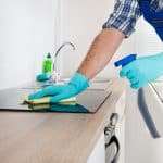 man with blue gloves cleaning the stove top