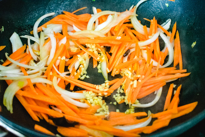 carrot, onion, and ginger in a black wok