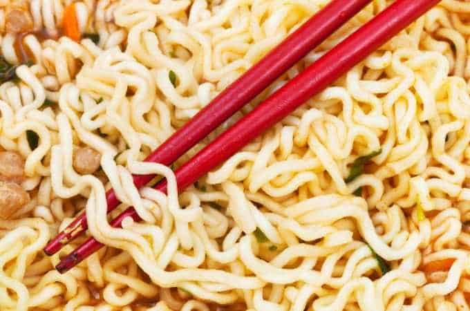 close up of ramen noodles with red chopsticks
