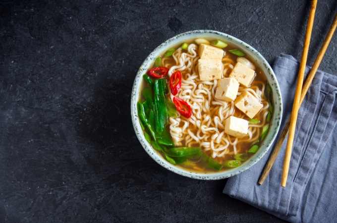 bowl of tofu ramen on a black background with