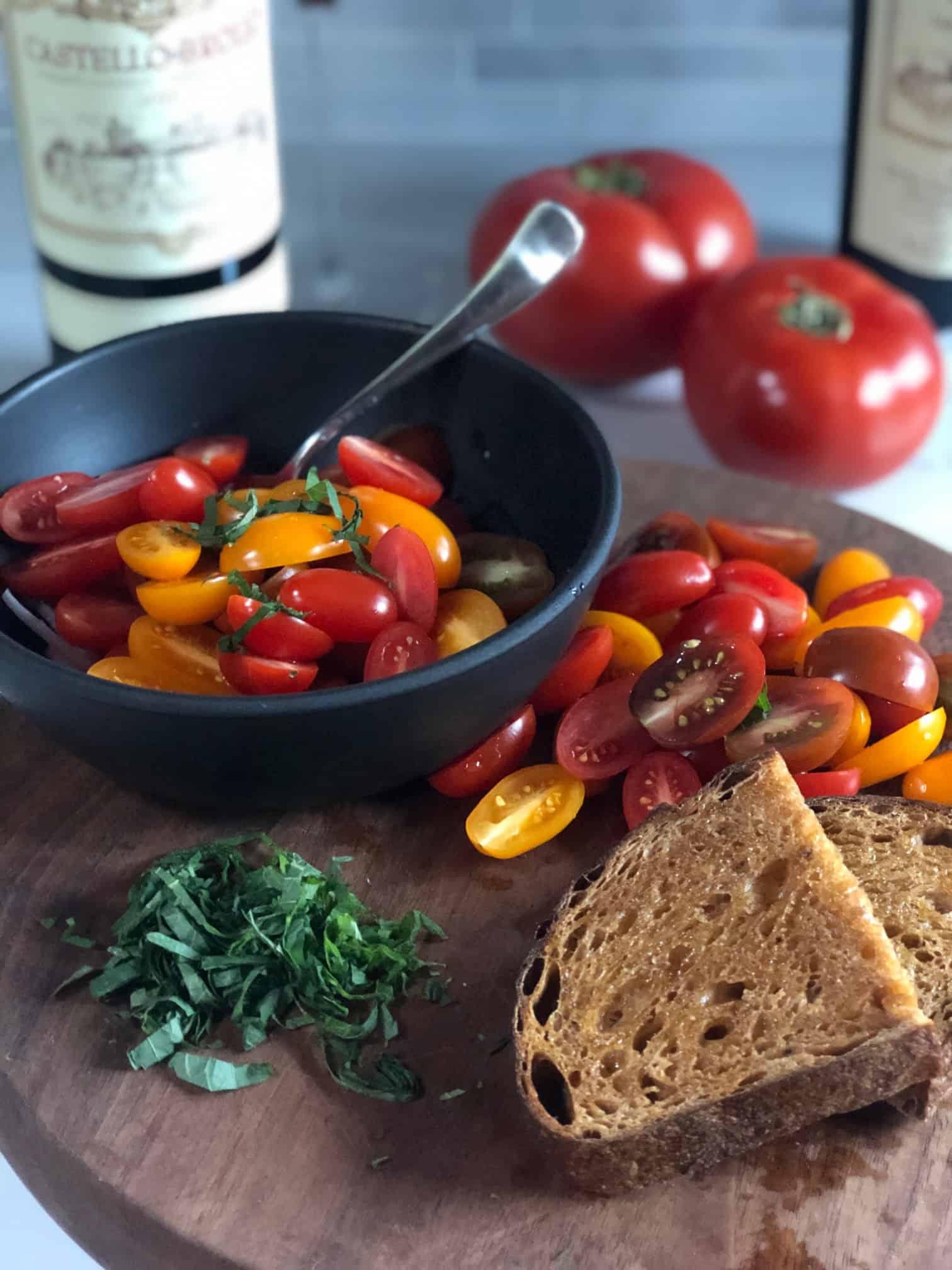 halved cherry tomatoes on a brown cutting board with bread
