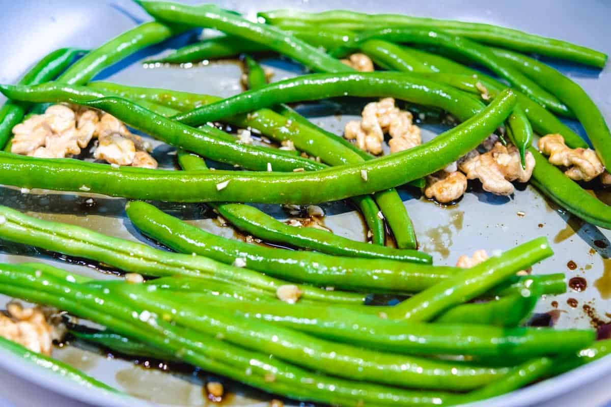 raw green beans and walnuts in gray pan