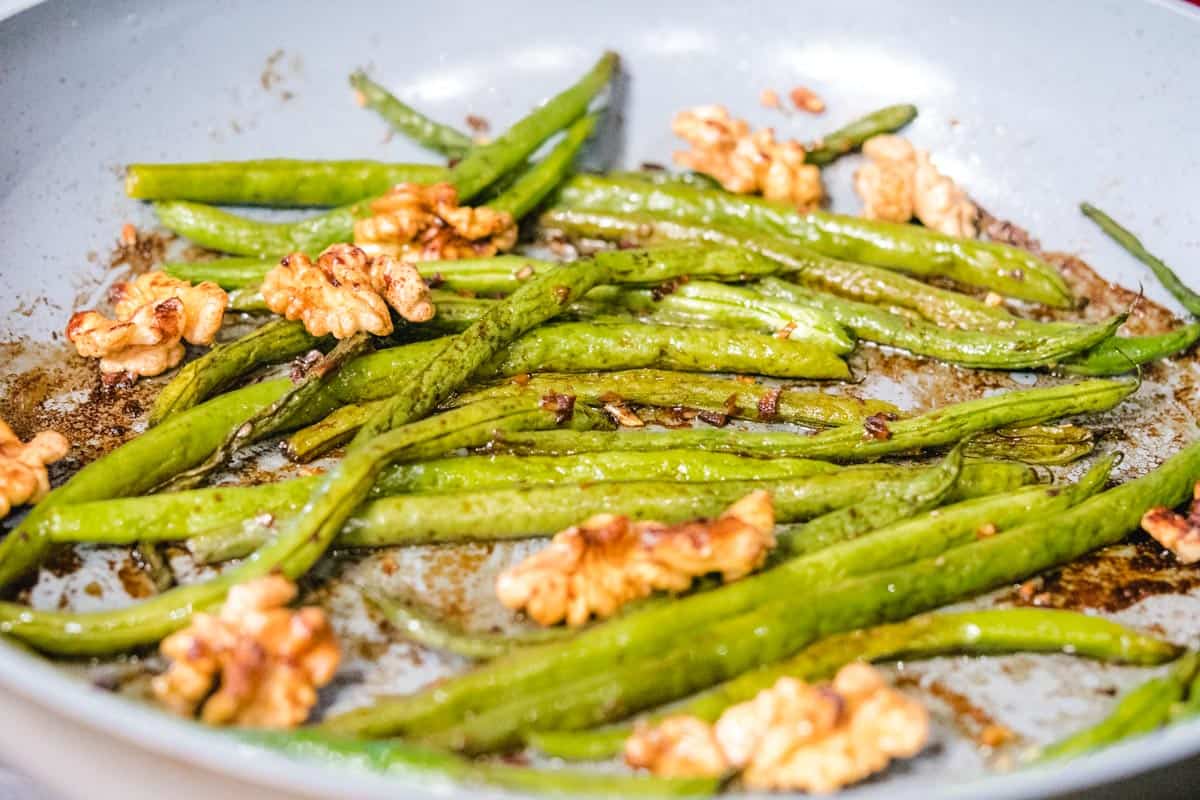 roasted walnuts and green beans in a pan