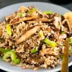 vegan wild rice fried rice on a gray round plate with a gold spoon