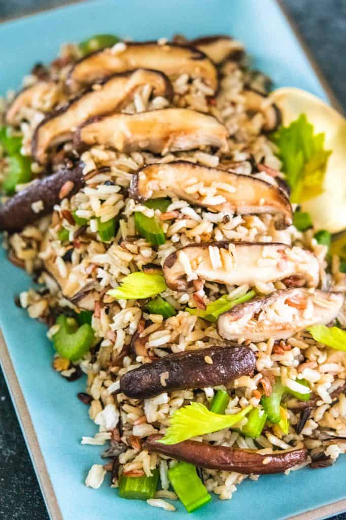 vegan wild rice fried rice on a blue plate with a gold spoon