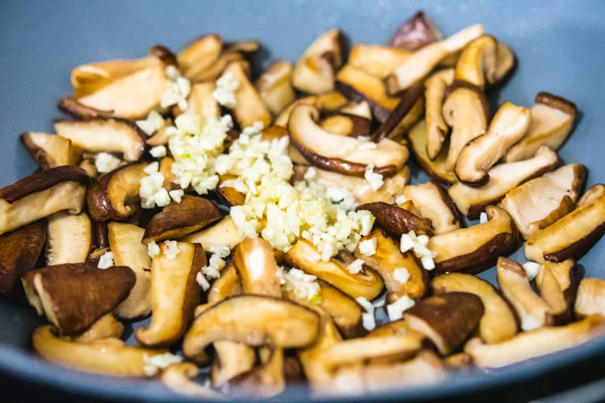 shiitake mushrooms in a wok with minced garlic