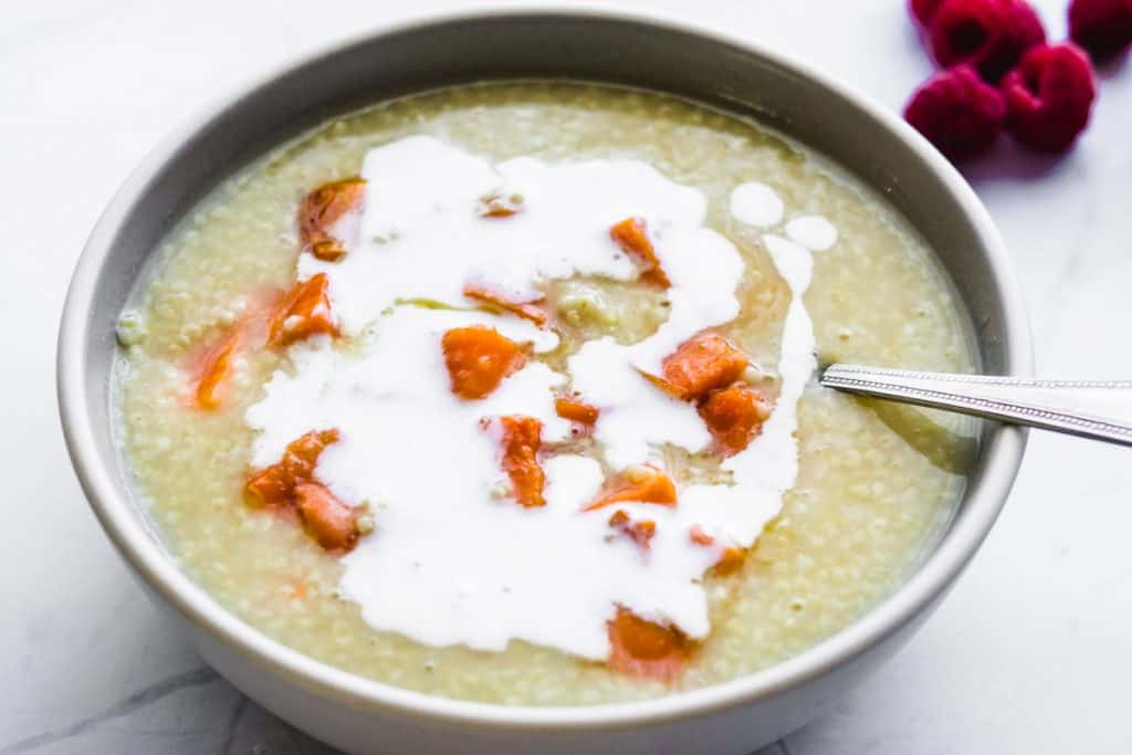 vegan millet porridge with roasted sweet potatoes in a bowl with a spoon and coconut milk