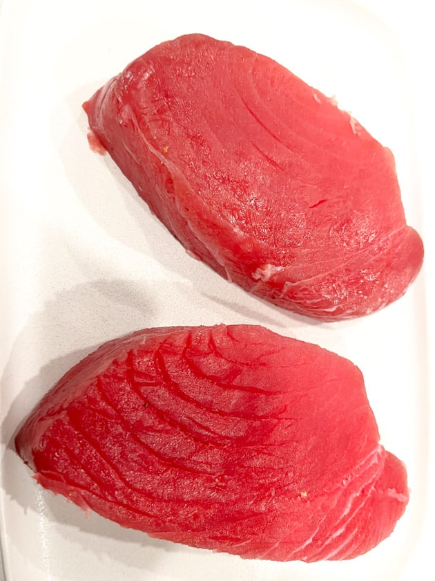 2 ahi tuna steaks on a white cutting board