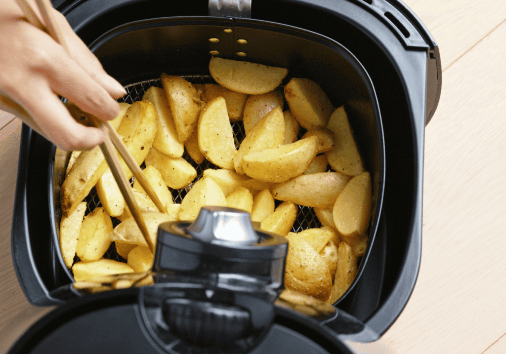potato wedges being turned with chopsticks in an air fryer