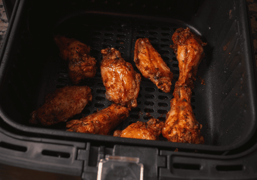 a pound of browned chicken wings in an air fryer basket