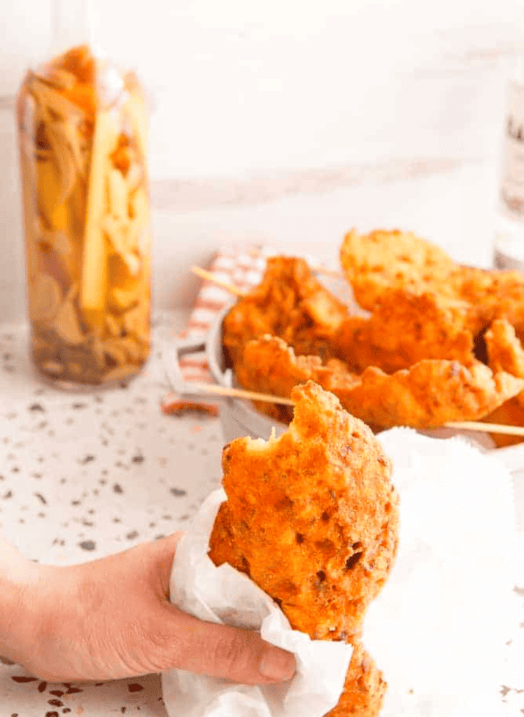 puerto rican codfish fritters with a hand holding one wrapped in a napkin