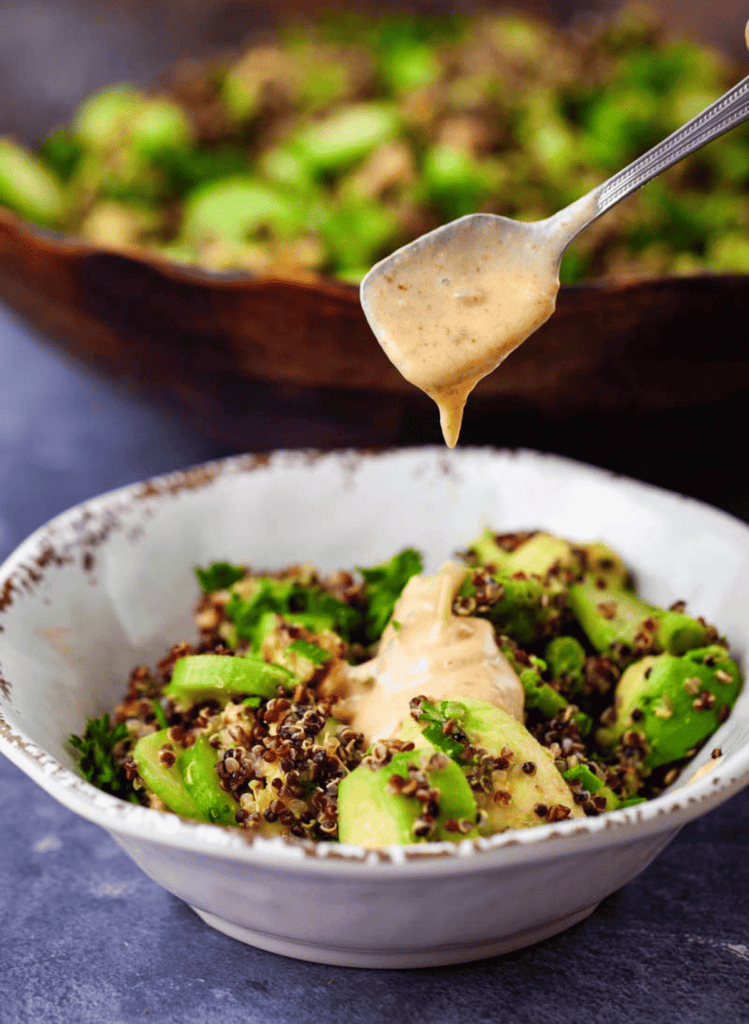 Quinoa avocado salad with a spoonfull of lemon dressing in a white bowl