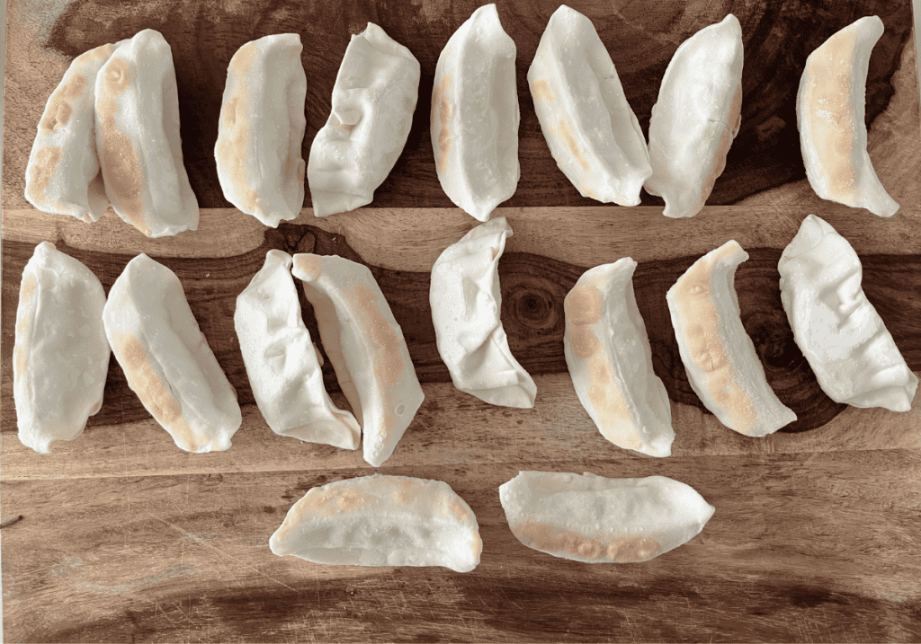 Trader Jo's frozen gyoza laid out on a wooden cutting board in rows.