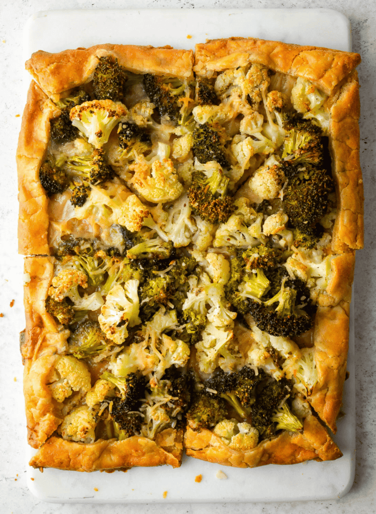 Cauliflower and Broccoli Vegetable Galette cut into triangles on a white cutting board