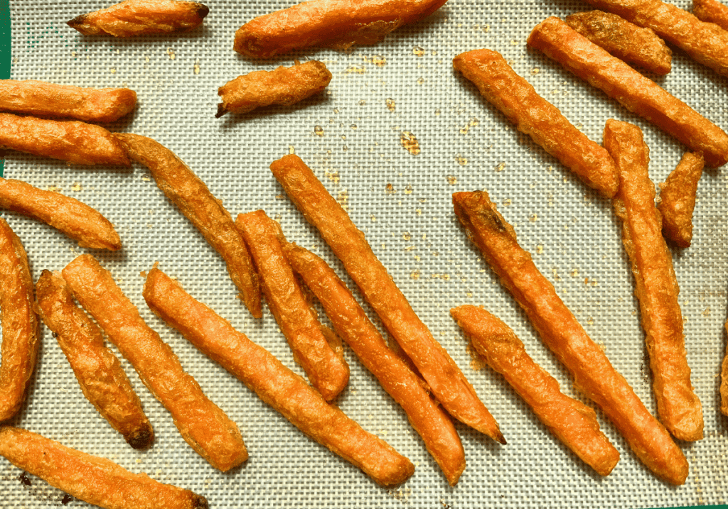 Cooked Trader Joe's sweet potatoes fries on a silicon baking sheet