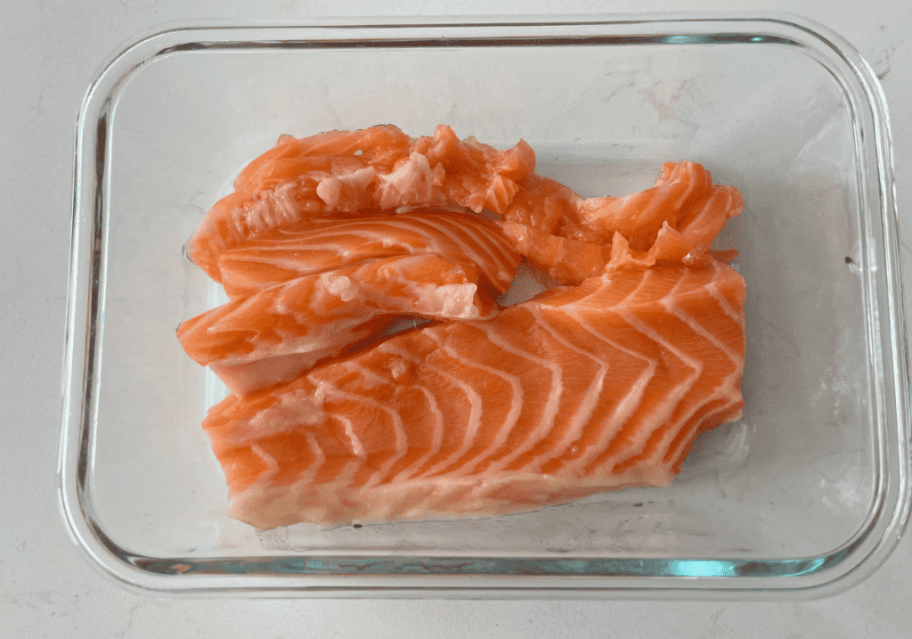 Raw salmon pieces in a glass baking dish.