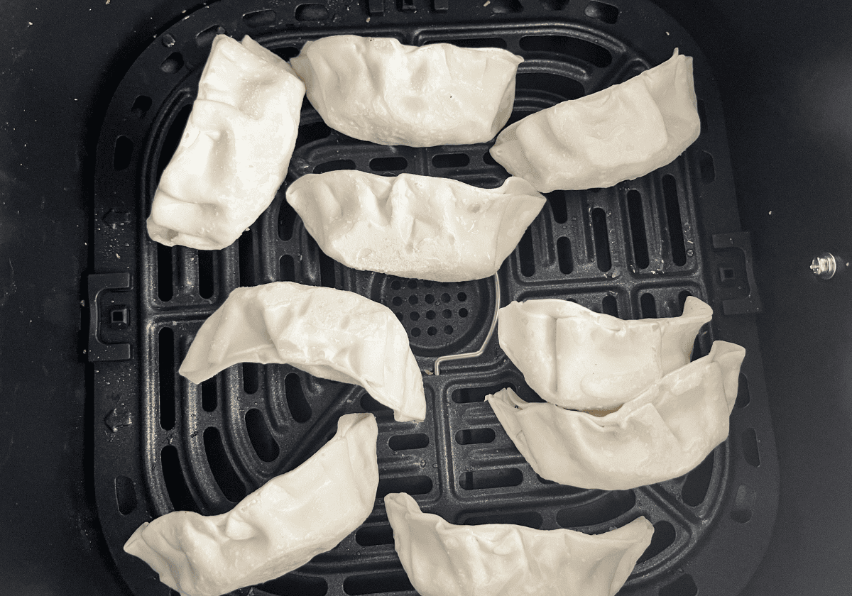 9 pieces of frozen Trader Joe's vegetable gyoza in an air fryer basket.