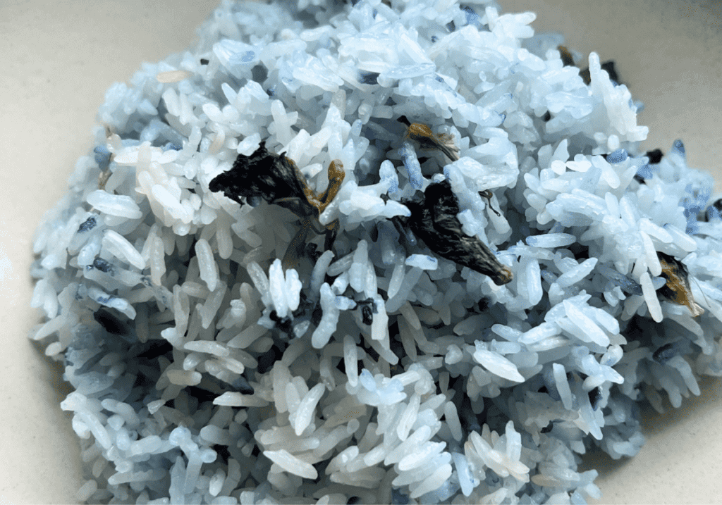 a mound of jasmine rice colored with buttery blue pea flowers