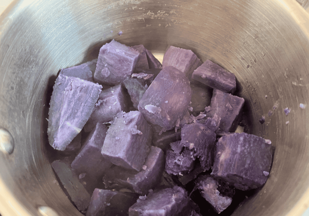 Drained and cooked purple potato chunks in a saucepan.