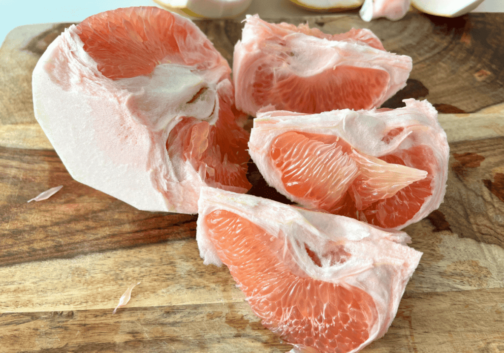 Pomelo segments on a wooden cutting board