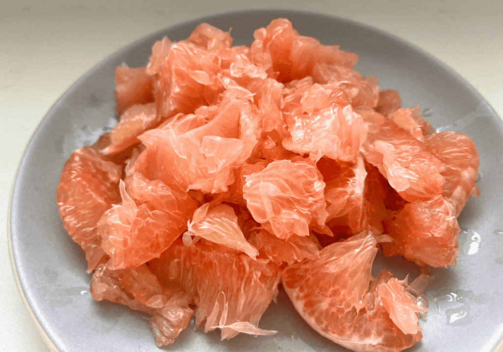 chunks of pomelo flesh on a gray round plate