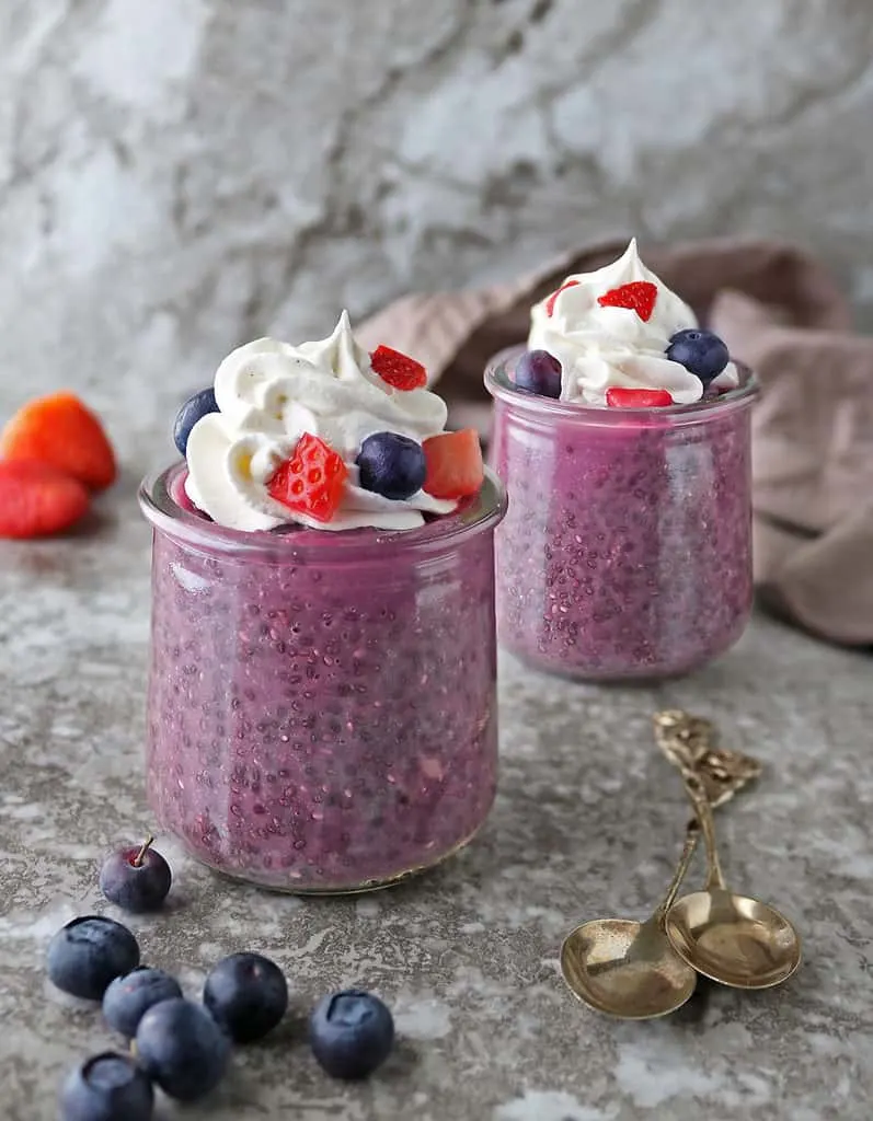 2 glass cups of Purple Sweet Potato Chia Pudding with berries and whipped cream on top