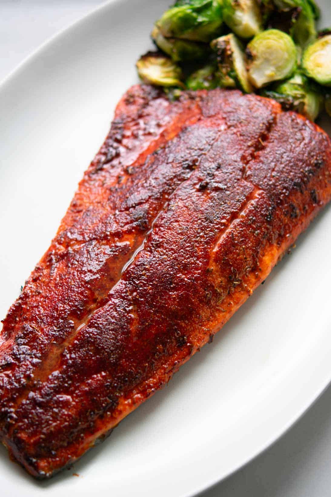 Pan seared sockeye salmon on a white oval plate with brussel sprouts