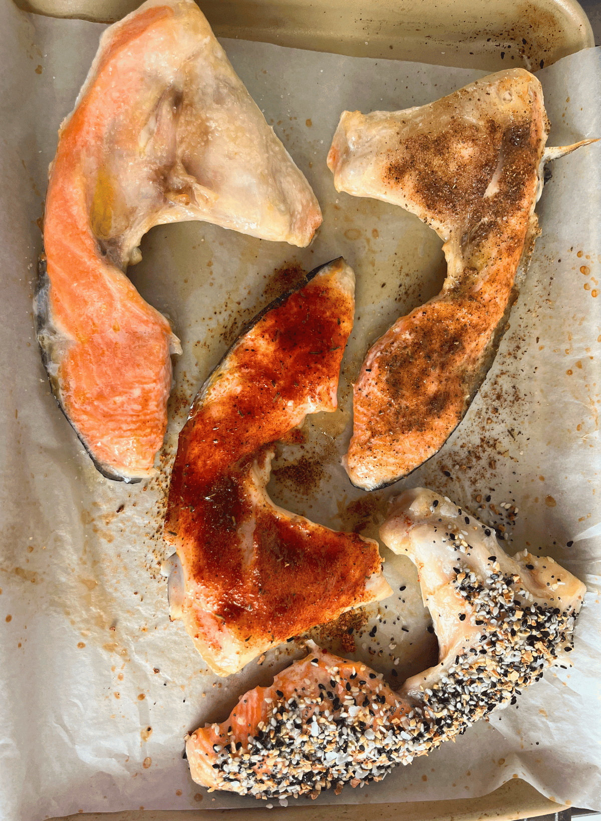 4 cooked salmon collars on a parchment lined gold baking sheet