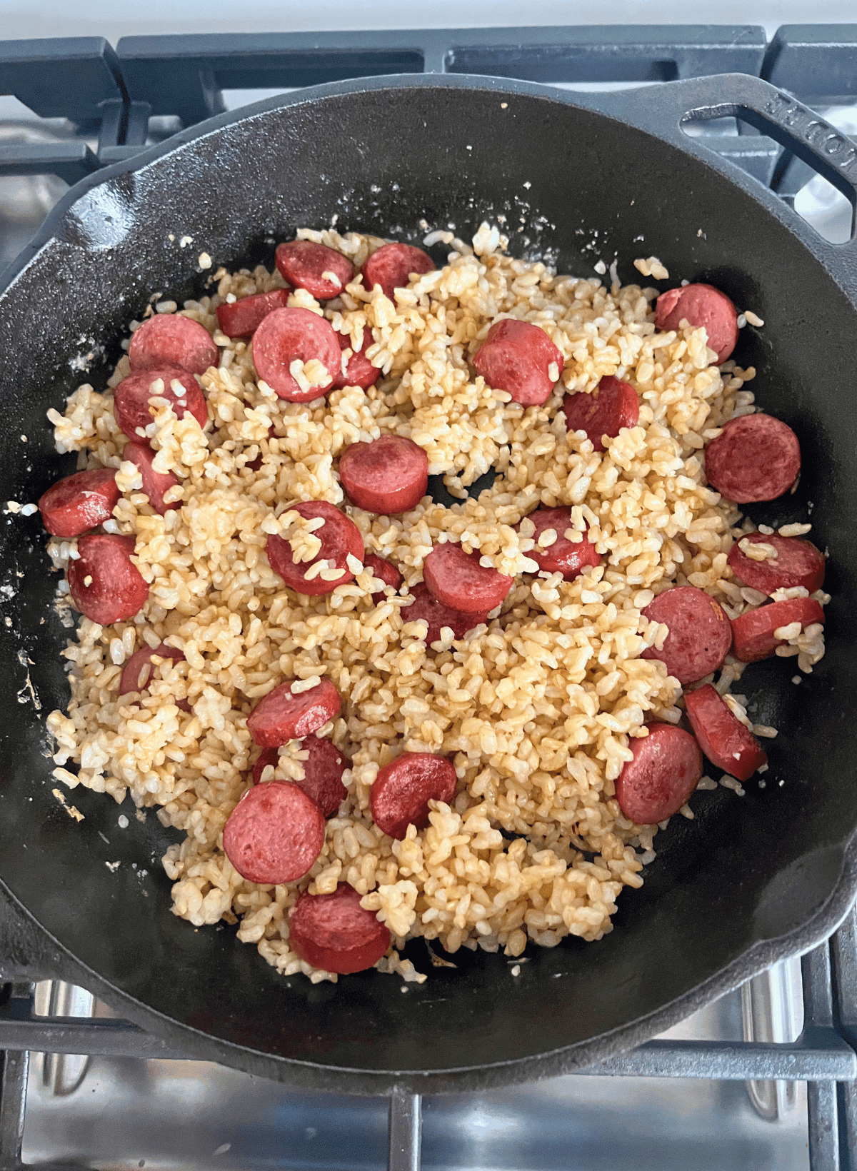brown rice and hot dog slices in a cast iron skillet