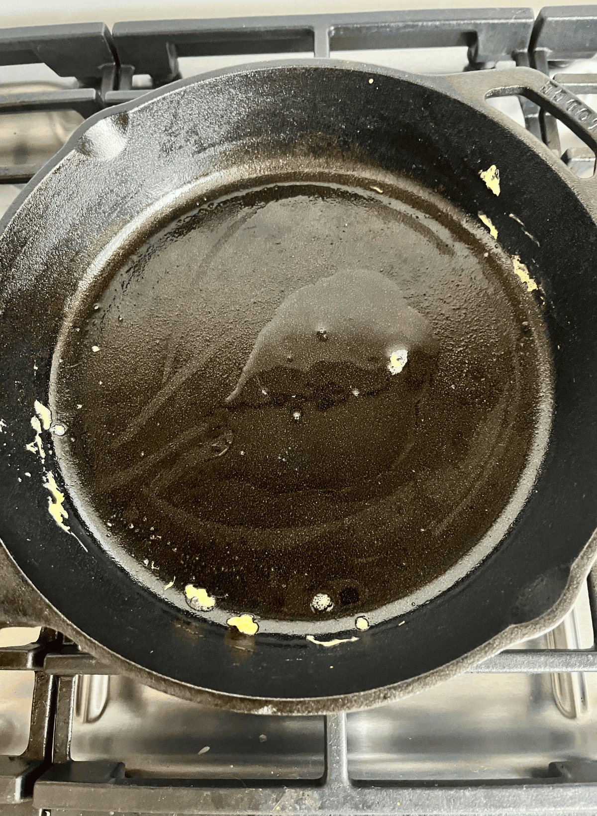 cast iron pan with residual scrambled egg and oil on a gas range