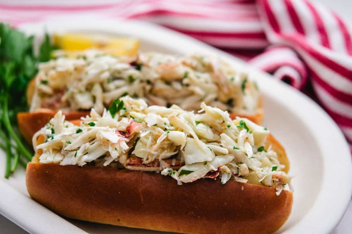 crab roll on a white plate with a red striped towel in the background