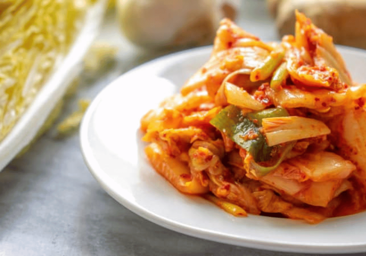 Close up shot of red napa cabbage kimchi on a white round plate