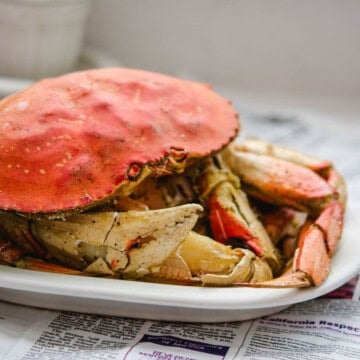 Dungeness crab with cracked legs one a white plate and Thanh Long butter sauce