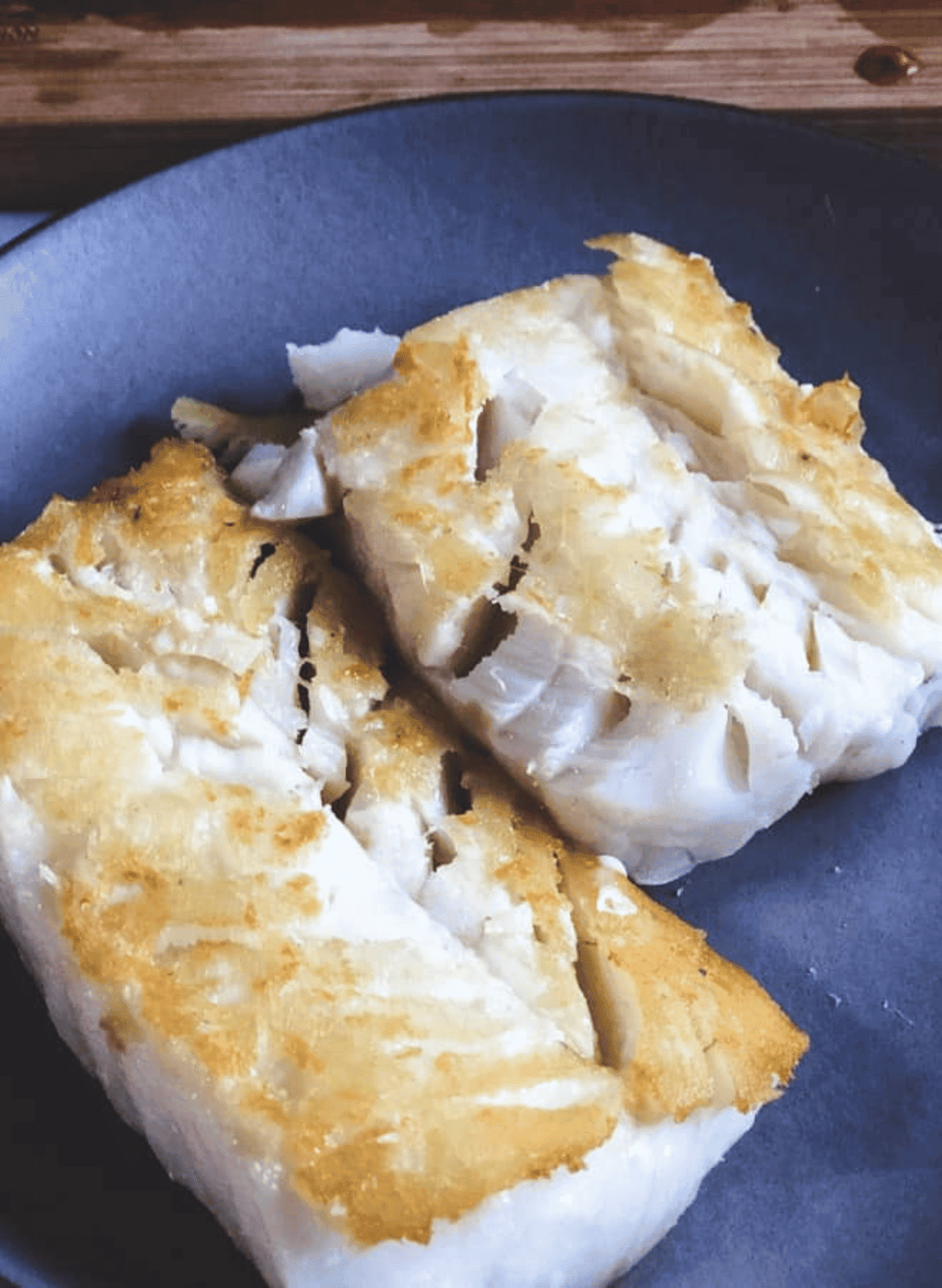 2 pieces of cooked cod filets on a gray plate