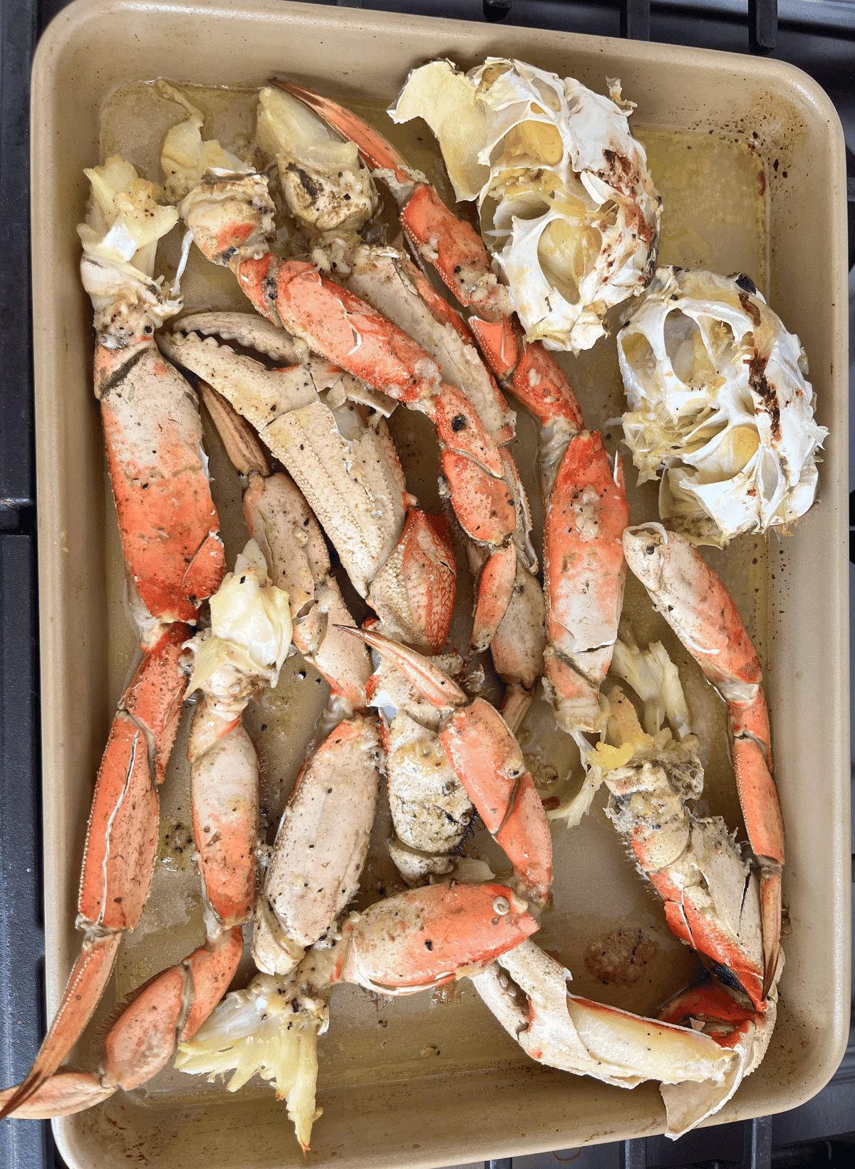 Roasted Dungeness crab on a gold sheet pan with garlic butter