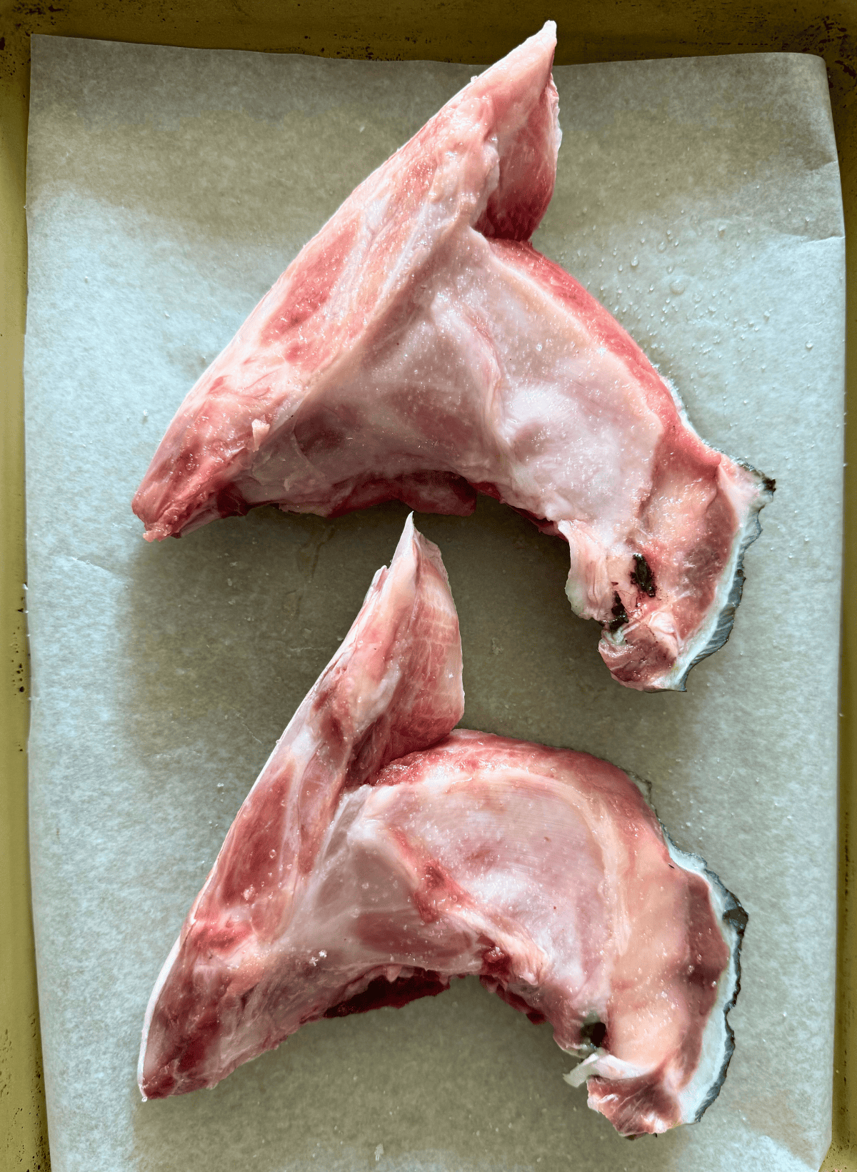 Zwei rohe Hamachi -Halsketten auf einem mit Pergament ausgekleideten Backblech