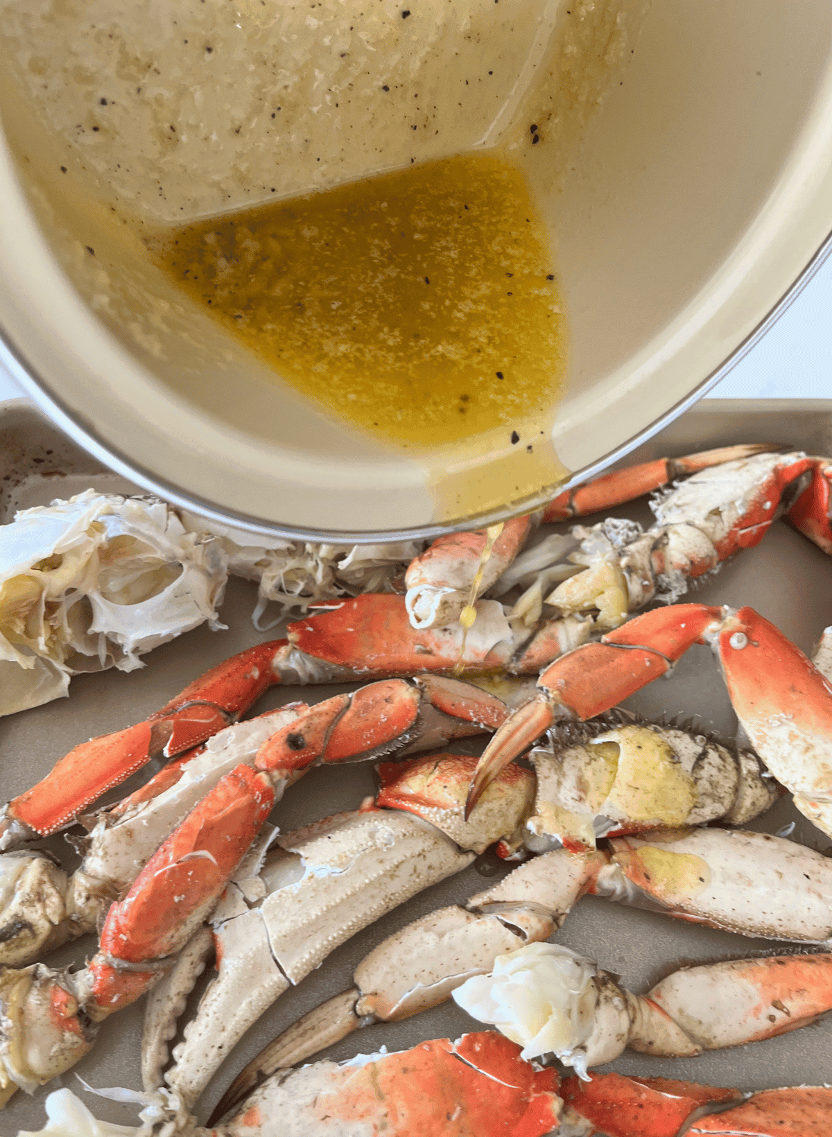 Roasted garlic crab sauce in a saucepan being poured onto cracked crab